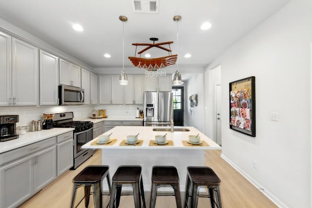107 Trailside Ln, Bastrop, TX 78602 - kitchen featuring stainless steel appliances, gray cabinetry, a breakfast bar, a sink, and decorative backsplash