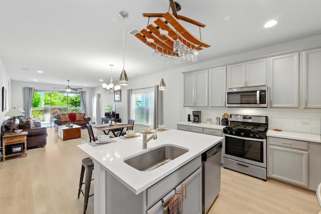 107 Trailside Ln, Bastrop, TX 78602 - kitchen featuring appliances with stainless steel finishes, a sink, open floor plan, light wood finished floors, and light countertops