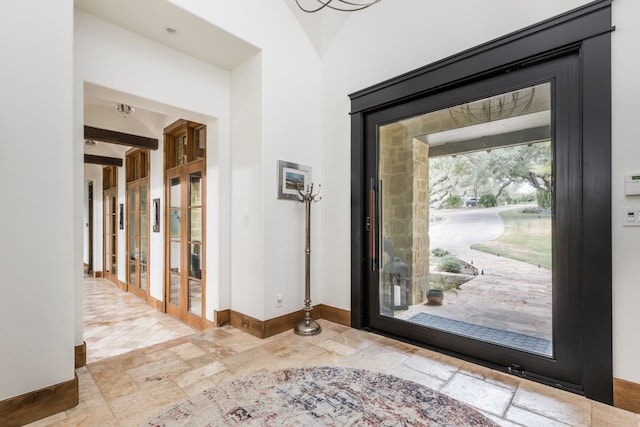 entryway featuring french doors, stone tile floors, and baseboards