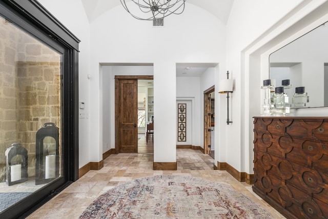 entryway with baseboards, lofted ceiling, visible vents, and stone tile floors