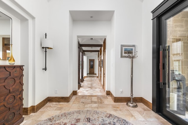 corridor featuring stone finish floor and baseboards