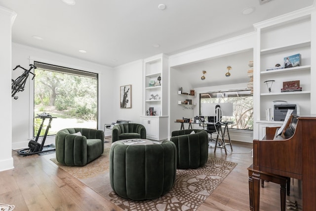 living area featuring baseboards, ornamental molding, wood finished floors, and built in features