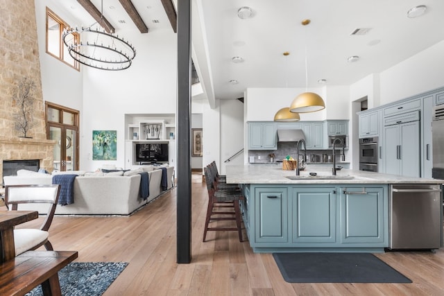 kitchen with oven, light wood finished floors, a sink, and a stone fireplace