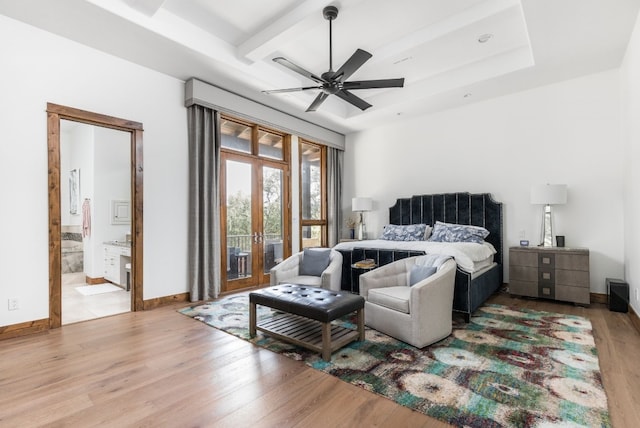 bedroom featuring baseboards, wood finished floors, access to exterior, a tray ceiling, and french doors