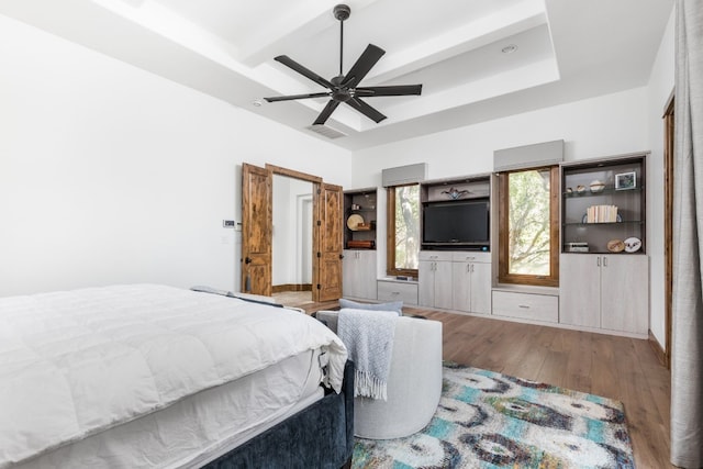 bedroom featuring a tray ceiling, beam ceiling, visible vents, ceiling fan, and wood finished floors