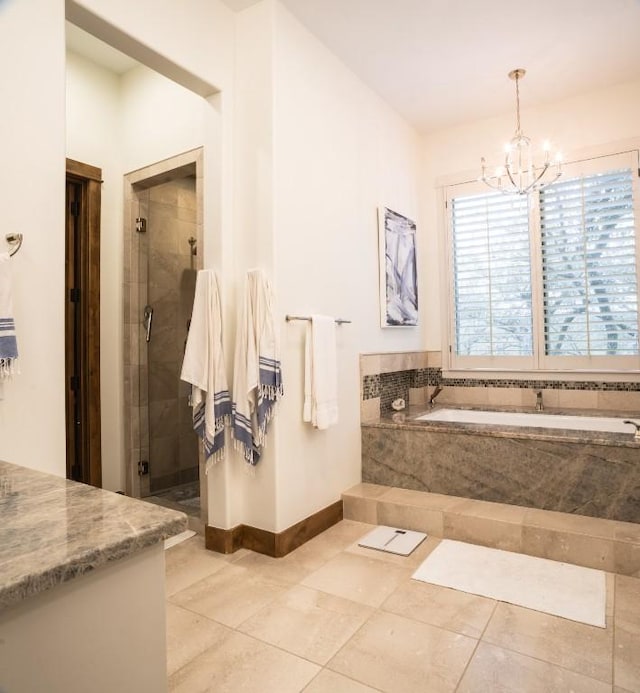 bathroom with a garden tub, a notable chandelier, a shower stall, tile patterned flooring, and baseboards