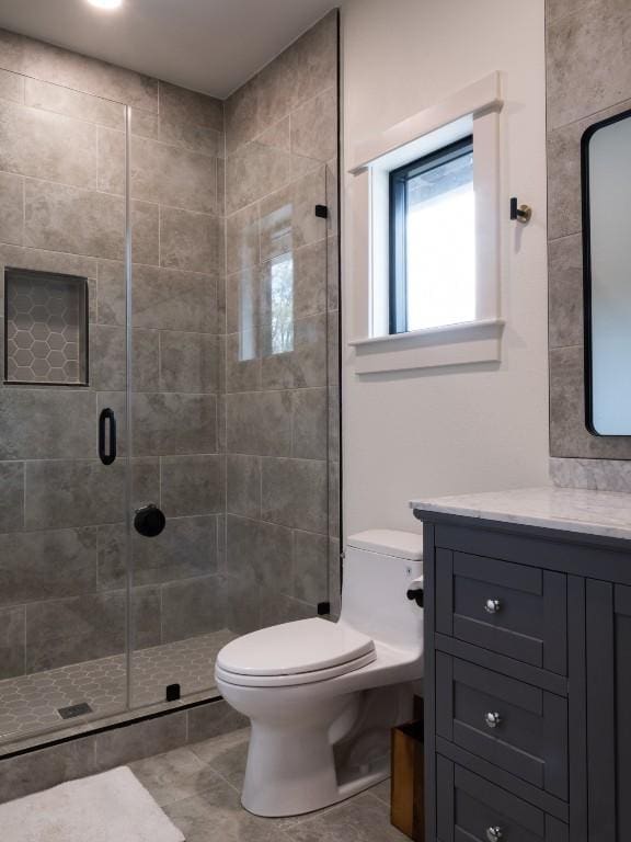 bathroom with vanity, tile patterned flooring, a shower stall, and toilet