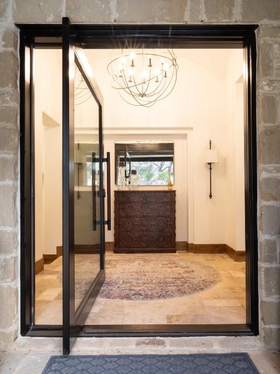 doorway featuring baseboards and an inviting chandelier