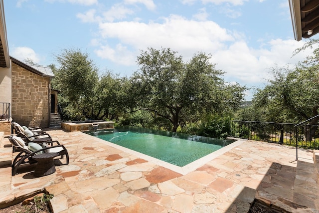 view of swimming pool featuring an infinity pool and a patio