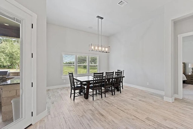 dining space with an inviting chandelier, light wood-style flooring, visible vents, and baseboards