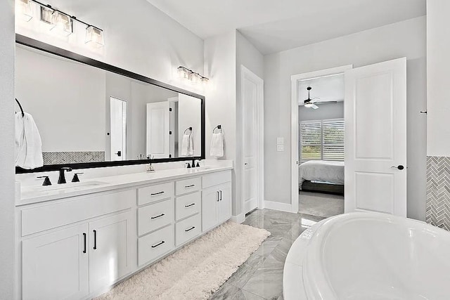 ensuite bathroom with marble finish floor, double vanity, a sink, and a bathing tub