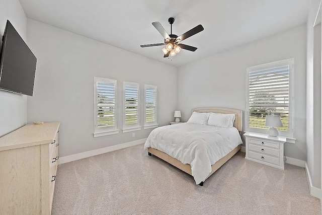 bedroom with light carpet, ceiling fan, and baseboards