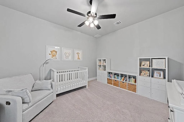 bedroom featuring carpet, visible vents, ceiling fan, and a crib