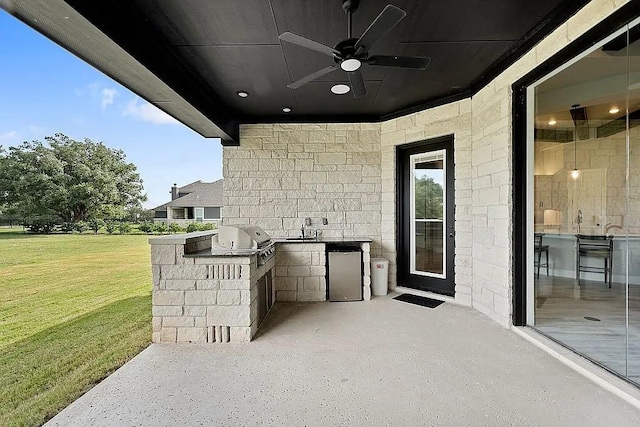 view of patio with exterior kitchen, a sink, grilling area, and a ceiling fan