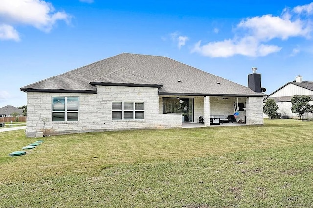 rear view of house featuring a chimney, a shingled roof, a lawn, a ceiling fan, and a patio area