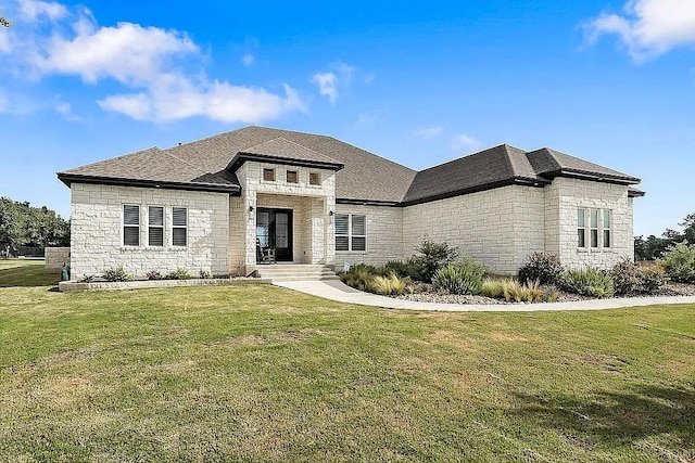 view of front of home with stone siding, roof with shingles, and a front yard