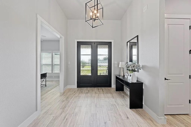 foyer entrance featuring a chandelier, french doors, wood finished floors, and baseboards