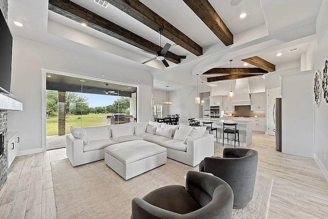 living area featuring ceiling fan, beamed ceiling, light wood-style flooring, and baseboards