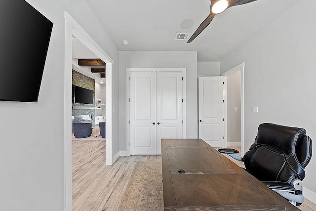 office space featuring a ceiling fan, visible vents, baseboards, light wood-type flooring, and beam ceiling