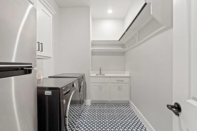 clothes washing area with washer and dryer, a sink, and baseboards