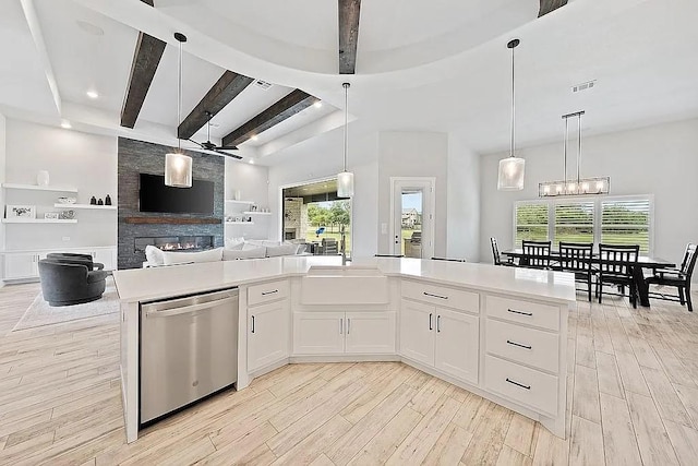 kitchen featuring dishwasher, open floor plan, light countertops, light wood-style floors, and beam ceiling