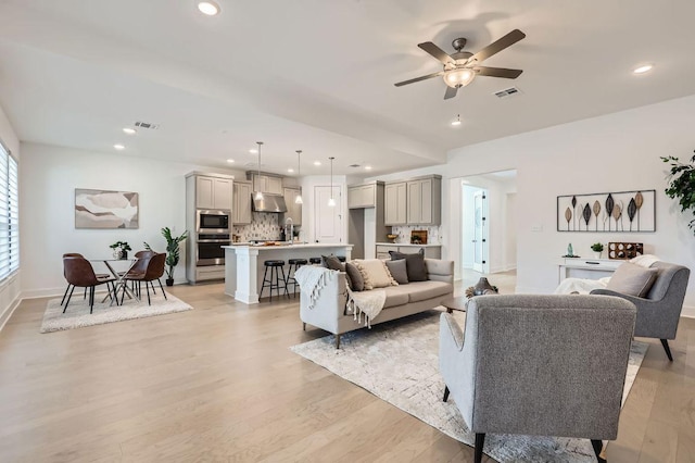 living room with recessed lighting, visible vents, and light wood finished floors