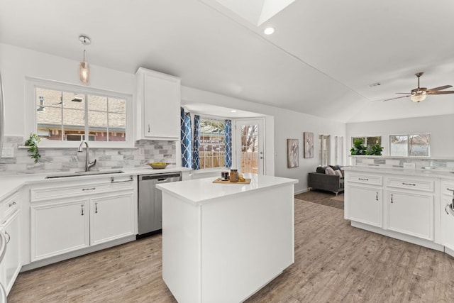 kitchen with a sink, plenty of natural light, vaulted ceiling, and dishwasher