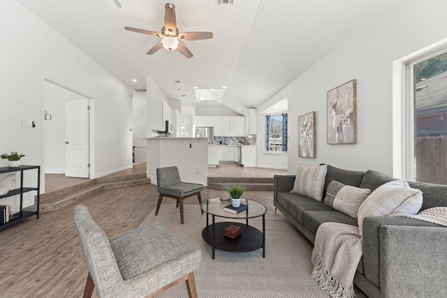 living room with lofted ceiling, ceiling fan, plenty of natural light, and light wood-style flooring