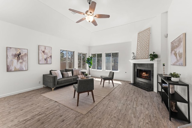 living area with ceiling fan, a fireplace, wood finished floors, and baseboards