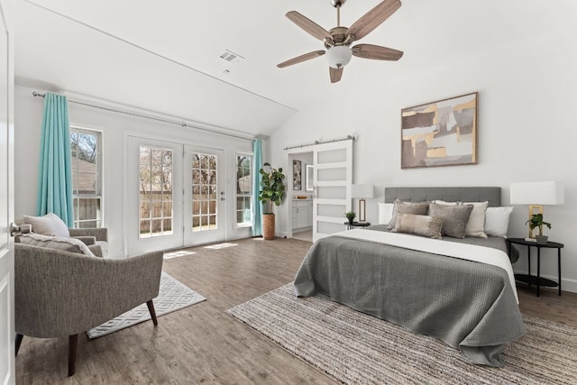 bedroom with a barn door, visible vents, lofted ceiling, wood finished floors, and access to outside