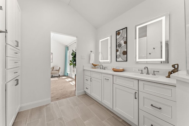 full bathroom featuring lofted ceiling, double vanity, baseboards, and a sink