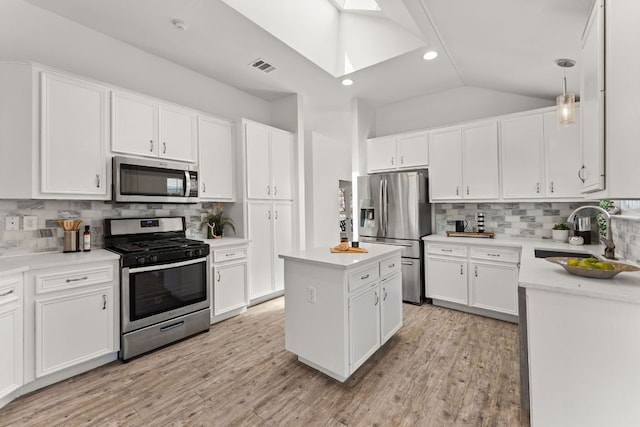 kitchen featuring stainless steel appliances, a kitchen island, a sink, visible vents, and lofted ceiling with skylight