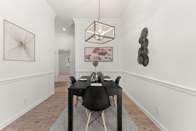 dining room with light wood-style floors, a notable chandelier, baseboards, and crown molding