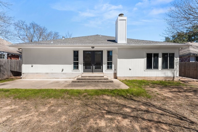 back of house with entry steps, a chimney, fence, french doors, and a patio area