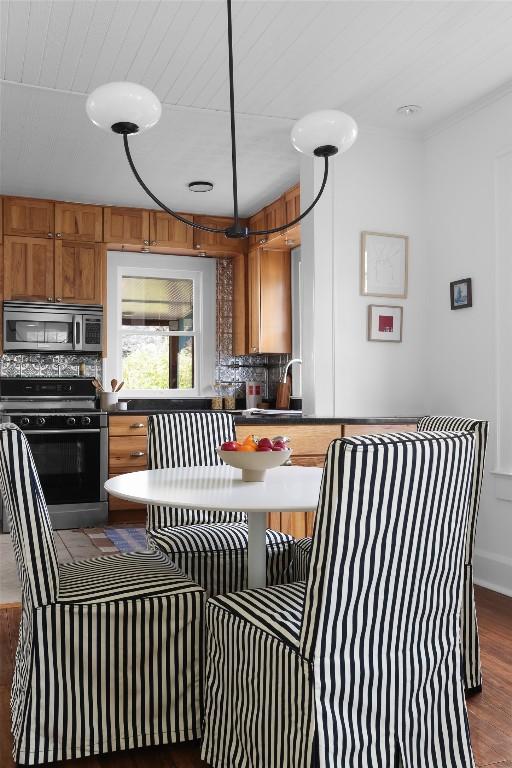 kitchen with a sink, brown cabinetry, black range, tasteful backsplash, and stainless steel microwave