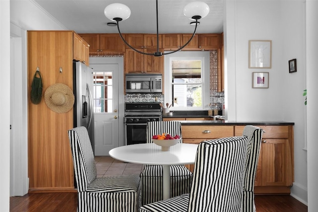 kitchen with appliances with stainless steel finishes, brown cabinetry, plenty of natural light, and tasteful backsplash