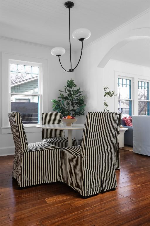 interior details featuring crown molding, arched walkways, and wood finished floors