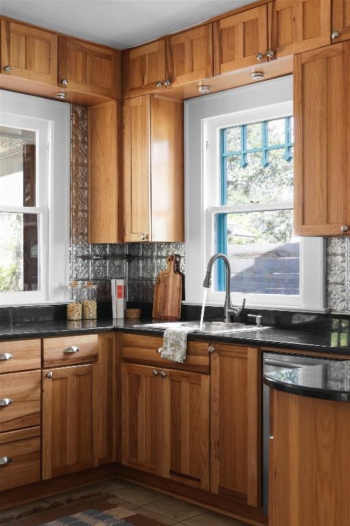 kitchen with brown cabinetry, dark countertops, and dishwasher