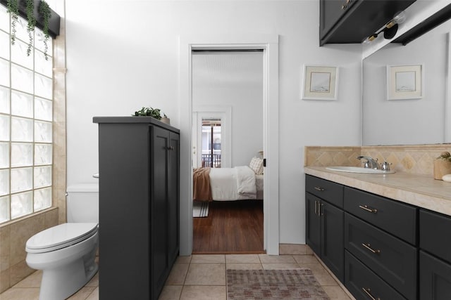 bathroom featuring decorative backsplash, toilet, connected bathroom, vanity, and tile patterned floors