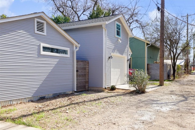 view of side of home featuring a garage, driveway, and fence