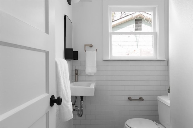 bathroom with plenty of natural light, a sink, toilet, and tile walls