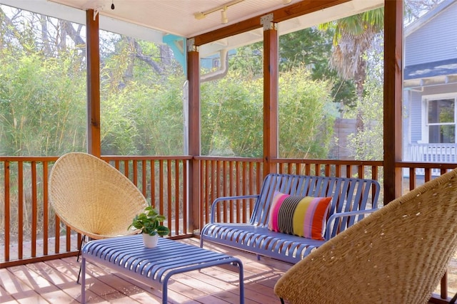 sunroom with rail lighting and a forest view