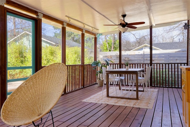 sunroom featuring a ceiling fan, a wealth of natural light, and rail lighting