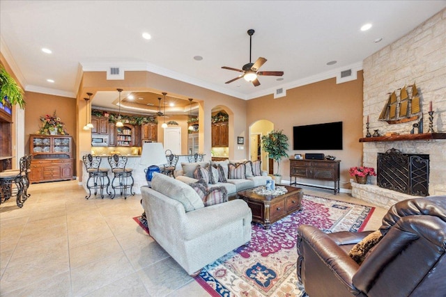 living area with a fireplace, visible vents, arched walkways, and light tile patterned flooring