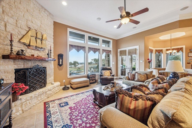 tiled living room with ornamental molding, a stone fireplace, ceiling fan with notable chandelier, french doors, and recessed lighting