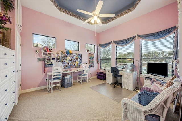 carpeted office featuring a ceiling fan, a raised ceiling, and baseboards