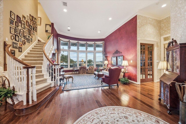 living area featuring ornamental molding, hardwood / wood-style flooring, a high ceiling, and visible vents