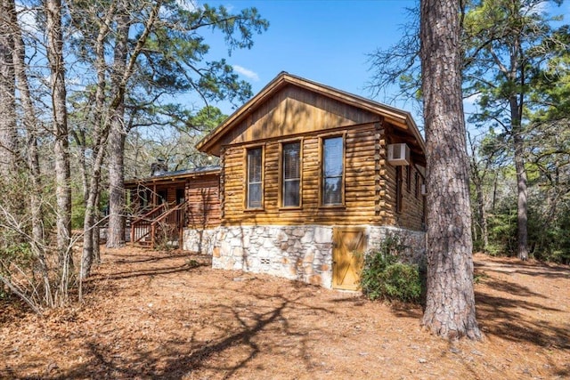 view of side of property featuring log exterior and a wall mounted air conditioner