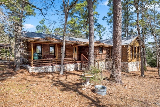 log home with covered porch, metal roof, and log siding