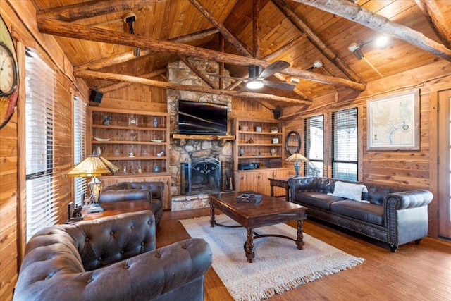 116 Yucca Ln, Bastrop, TX 78602 - living room with a wood ceiling with exposed beams, wood walls, built in shelves, wood finished floors, and a fireplace
